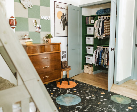 A boys bedroom with a space-themed rug and an open organized closet